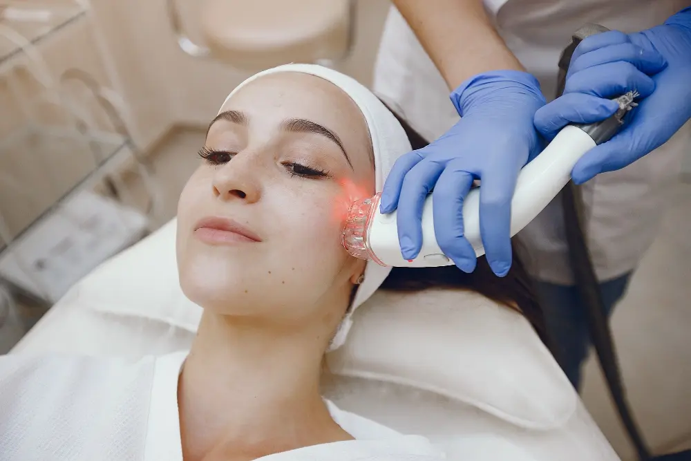 Practitioner performing handheld red light therapy treatment on patient