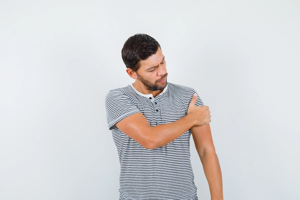 Person struggling to lift arm due to shoulder stiffness