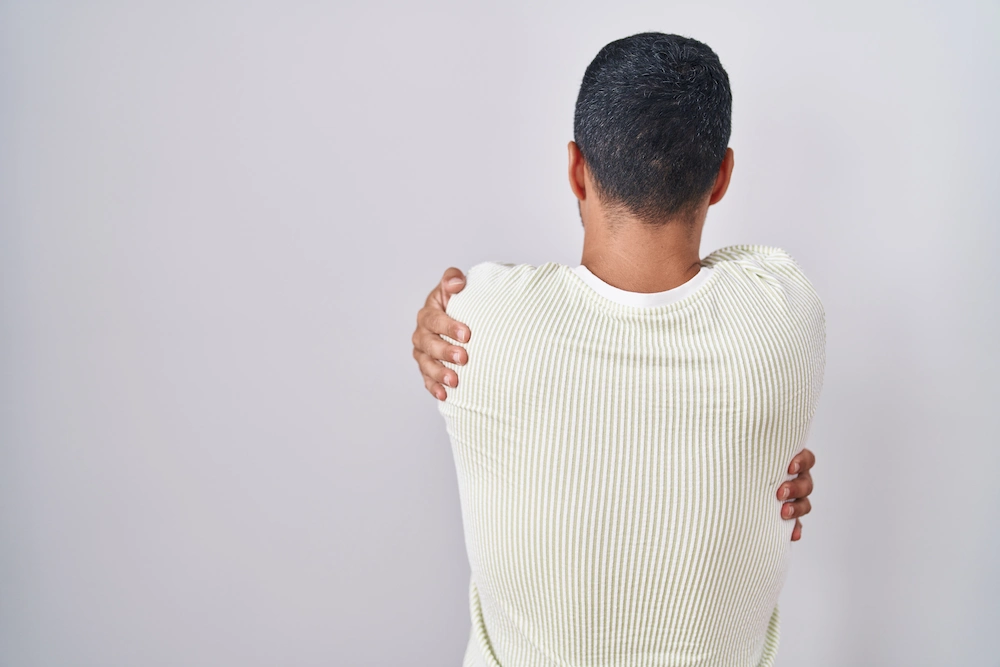 Person holding the shoulder and upper back due to localized pain